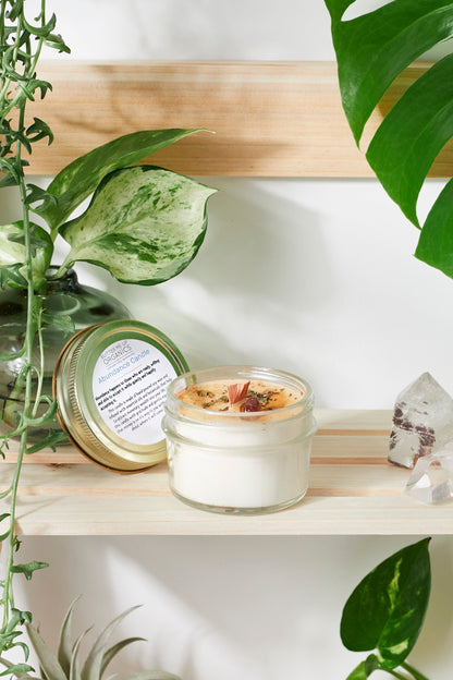 Abundance Ritual Candle in hand-poured soy wax, surrounded by greenery and crystals, symbolizing prosperity and gratitude.